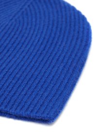 Berretto lavorato a maglia blu con una texture a costine, caratterizzato da una finitura morbida e pelosa. Il bordo ha una forma arrotondata, che mette in risalto il suo design accogliente.
