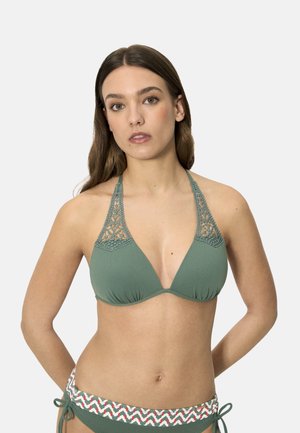 Joven mujer que lleva un bikini de halter verde con detalles de ganchillo y parte inferior a juego con cintura estampada y lazos laterales.
