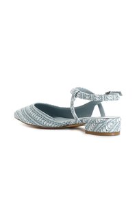 Zapato slingback tejido en azul claro con puntera afilada y tacón bajo. Presenta un upper texturizado y una delgada correa en el tobillo.