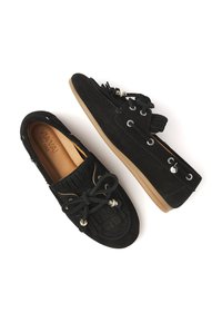 Schwarze Wildleder-Mokassinschuhe im Mokassin-Stil mit Fransendetails, Ösenakzenten und Schnürsenkeln. Mit einer weichen, beigen Gummisohle.