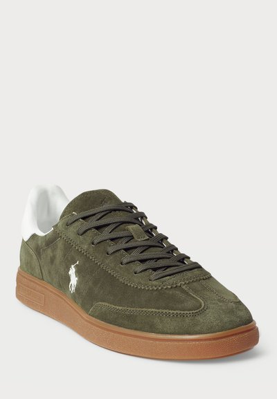 Olivengrønne ruskindsneakers med hvide syntetiske detaljer, kontrasterende brun gummisål og mørke snørebånd. Har broderet logo på siden.