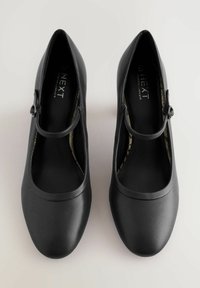 Pantofi negri Mary Jane cu vârf rotund, talpă de cauciuc și o bretea decorativă fixată cu o cataramă. Textură netedă și design minimalist.