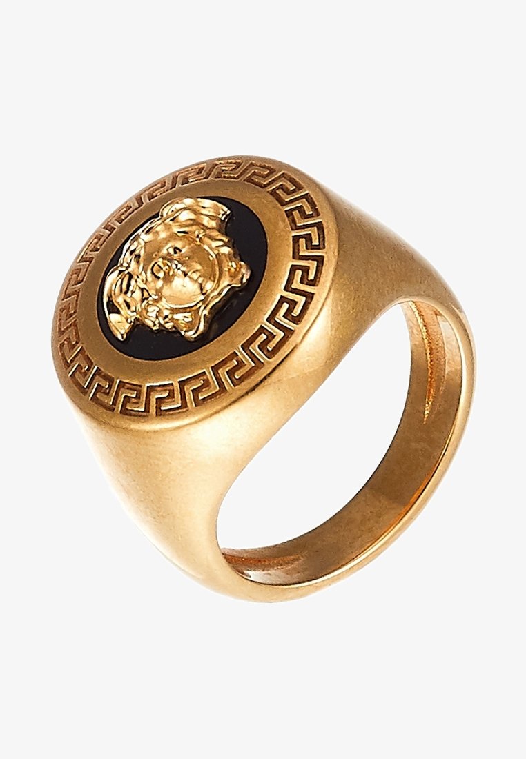 Bague à cachet en or avec un centre noir présentant une tête de lion en relief et un motif géométrique de clé grecque autour du bord.