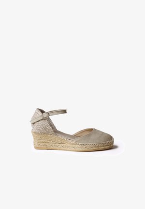 Chaussure à talon compensé espadrille beige avec dessus en toile, semelle en jute tressée, bride réglable à la cheville et design à bout rond.