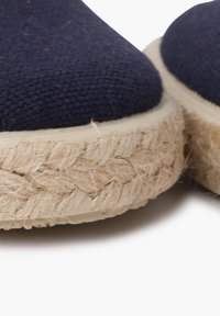 Tumesinavast kanvasest espadrillid, millel on punutud jute-tald ja paks, tekstureeritud looduslikest kiududest põhi. Ümar varvaste disain.