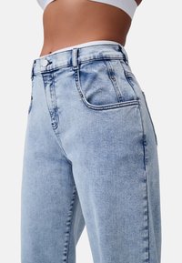 Jeans in denim blu chiaro a vita alta, dotati di cinque tasche, cuciture a contrasto e dettagli in metallo argentato, con una vestibilità comoda e una texture liscia.