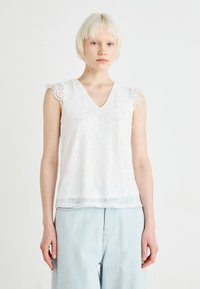 Hvit ermeløs topp med V-hals, med blonde detaljer på skuldrene og falden. Strukturert blomsterdesign gjennom hele.