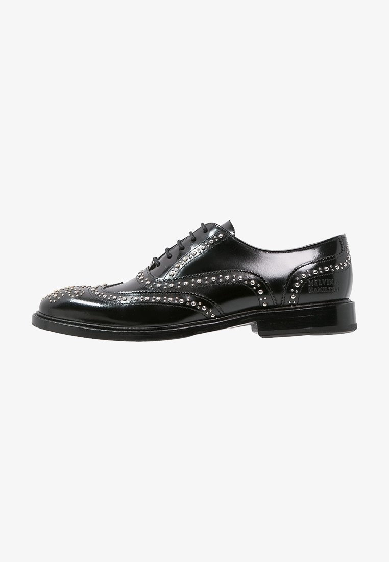 Chaussure brogue en cuir noir poli avec détails en clous argentés, lacets à l'avant, talon bas et contrefort de talon marqué.