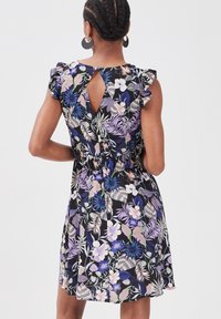 Robe à fleurs avec un fond noir, mettant en avant des manches volantes, une découpe en trou de serrure dans le dos, et une taille cintrée avec une jupe fluide.