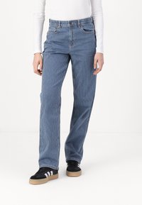 Blue striped wide-leg jeans made of cotton, featuring a high waist, front pockets, and belt loops. Paired with black sneakers.
