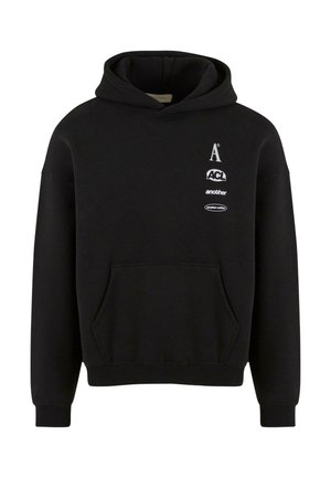 Sweat à capuche noir avec une poche frontale, cordon de serrage à la capuche et logos imprimés sur la poitrine. Le matériau semble doux et texturé.