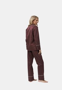 Pigiama bordeaux con pois, composto da una camicia con bottoni e pantaloni abbinati, con bordi bianchi. Tessuto morbido con una vestibilità comoda.