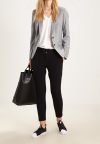 Gray blazer, white V-neck shirt, black slim-fit pants, black sneakers with white soles, and a black tote bag. Simple design, modern look.