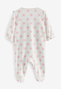 Combinaison bébé à manches longues en coton blanc avec de grands pois roses. Accents volantés aux épaules et design avec pieds. Texture douce.