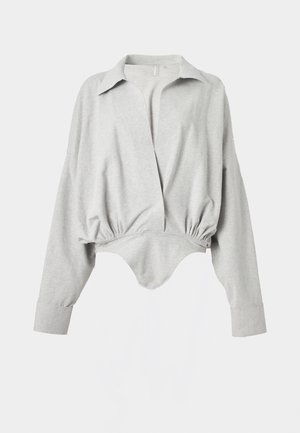 Šviesiai pilkas bodis su ilgomis rankovėmis, plačiais atvartais, elastinga juosmeniu ir spaustukais užsegimu tarp kojų, pagamintas iš minkšto, tampraus audinio.