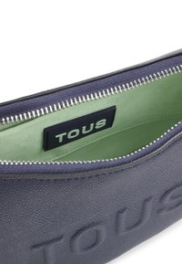 Navy teksturowana torba z wnętrzem w zielonym kolorze, z metalowym zamkiem błyskawicznym i czarną naszywką z logo "TOUS".