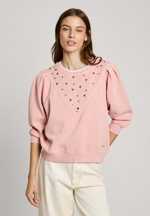 Sudadera rosa con mangas abullonadas y un diseño de diamante adornado con tachuelas metálicas en la parte delantera. Los puños y el dobladillo acanalados completan el look.