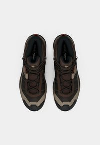 Καφέ και καμηλό παπούτσια για πεζοπορία με υφασμάτινη υφή, δαντελωτό πλέγμα, κορδόνια με κούμπωμα και λαστιχένιες σόλες με ανθεκτικό ανάγλυφο σχέδιο.