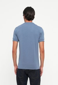 Polo shirt in light blue, made of cotton blend. Features a ribbed collar and short sleeves, with a smooth texture and fitted design.