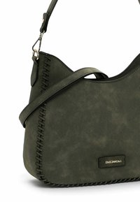 Sac à bandoulière vert olive en faux suède, avec un accent cousu le long du bord et une plaque en métal avec logo à l'avant.