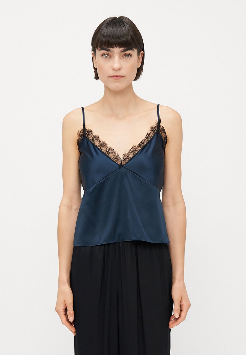 Jūras zila satīna kamizole ar mežģīnēm ap kakla izgriezumu un regulējamiem siksniņām. Gluda tekstūra, brīva piegriezuma un viegla spīduma.