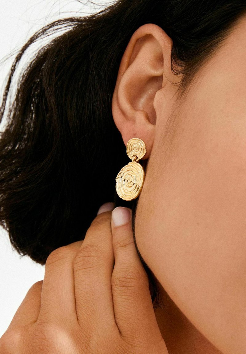 Złote kolczyki spiralne o teksturowanym, warstwowym wzorze. Okrągłe kształty z polerowanym wykończeniem, zawieszone na małym sztyfcie.