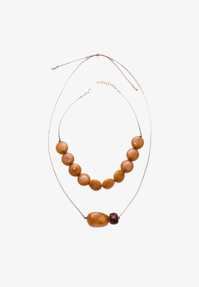 Hnedý náhrdelník z korálok s hladkým, lesklým povrchom. Dva pramene: jeden s väčšími guľatými korálkami, druhý s jedným väčším oválnym korálkom a akcentmi.