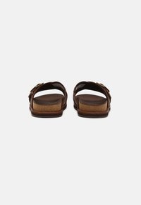 Sandales en cuir marron avec un dos ouvert, semelle intermédiaire en liège et une boucle en métal en accent. Semelle texturée pour le confort.