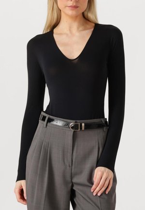 Zwarte lange mouwen bodysuit met een diepe V-hals, gecombineerd met grijze geplooide broek en een glanzend zwarte riem met een ronde gesp.