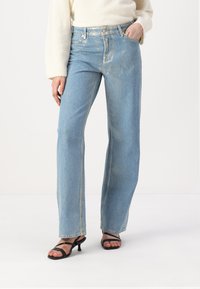 Jeans de pierna ancha de un azul claro, elaborados en denim con acentos deslavados, que cuentan con una clásica cinturilla con botones, cinco bolsillos y detalles de costura lateral.