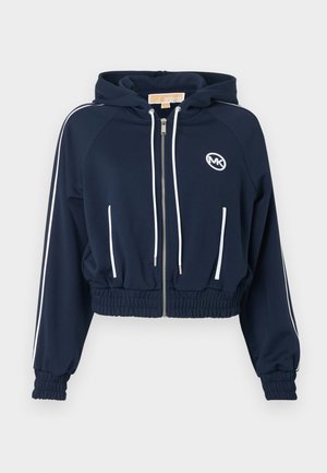 Marineblå kort zip-up hættetrøje med hvide snore, sidelommer, forlommer, elastiske manchetter og kant samt MK-logo på brystet.
