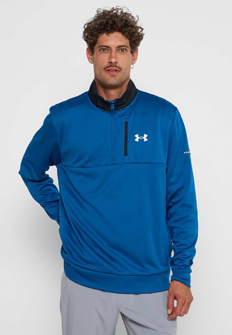 Pull bleu en polaire avec un col zippé mi-hauteur, des accents noirs et un logo brodé sur la poitrine. Texture lisse avec des manches longues.