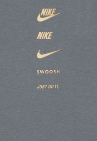Grå tygtröja med tre gyllene Nike-loggor och texten "SWOOSH" och "JUST DO IT" i en fet, tydlig font nedanför.
