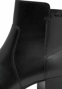 Schwarze Leder-Stiefelette mit schmaler Silhouette, glatter Textur, dezenten Nähten und einem stabilen Blockabsatz.