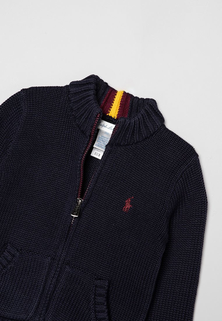 Marineblauer Strick-Zipfelpullover mit geripptem Kragen, der rote und goldene Streifen aufweist, Fronttaschen und ein gesticktes Logo auf der Brust.