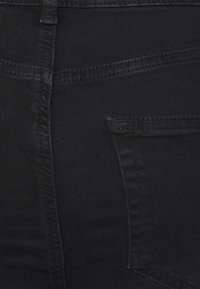 Jeans de ganga preta com uma textura suave, apresentando um bolso traseiro, costura visível e um design de cintura alta.