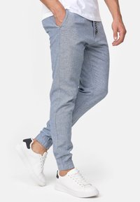 Lichtblauwe joggerbroeken met een gestructureerd patroon, voorzien van elastische boorden, zijzakken en een drawstring taille, gecombineerd met witte sneakers.