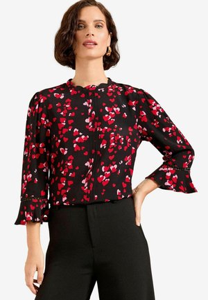 Blusa nera con motivi a cuori rossi e rosa, con maniche lunghe e polsini arricciati, scollatura rotonda e chiusura con bottoni sul davanti.