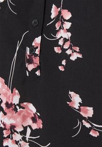 Blusa di tessuto nero con stampa floreale rosa, dotata di una chiusura a bottoni e una texture liscia. Il design include delicati steli e petali.