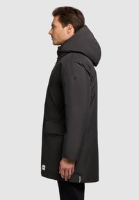 Sort parka jakke med hætte, der har en lige pasform, forlommer og minimal branding. Glat tekstur med en mat finish.