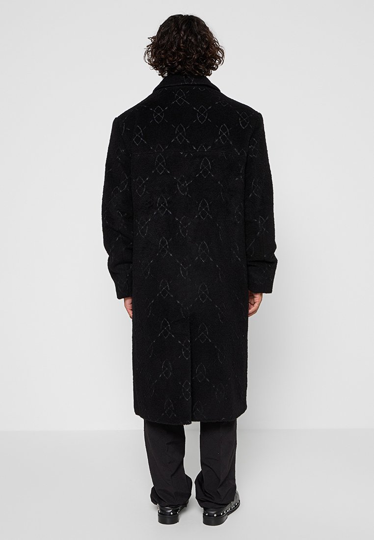 Manteau noir avec un motif texturé et un subtil éclat, doté d'un col haut et de manches longues. Silhouette épurée et droite.