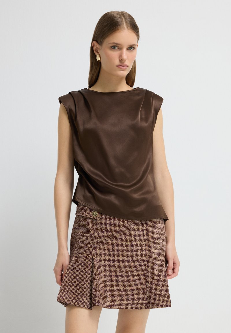 Brun satin uden ærmer toppet med en tekstureret brun mønstret mini nederdel med en sidefure og en guldaccent knap.