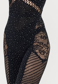 Black bodysuit featuring a mesh design with rhinestone accents, cut-out sections, and lace detailing on the legs.
