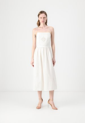 White linen dress with a fitted bodice, square neckline, and adjustable straps; features a textured diamond pattern on the front.