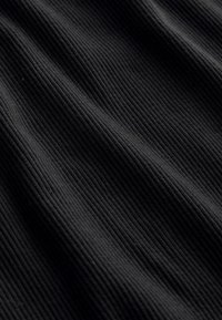 Zwarte geribbelde stof met een gestructureerd patroon van verhoogde verticale lijnen, met zachte plooien en draperieën.