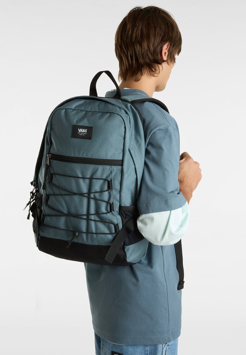 Zaino in tessuto teal con base nera, caratterizzato da una tasca frontale con zip, dettagli in corda elastica e spallacci regolabili imbottiti.
