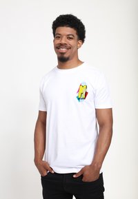 Hvid bomulds t-shirt med et farverigt MTV-logo grafik på venstre brystområde; rund hals og korte ærmer.