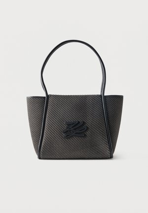 Sac fourre-tout noir texturé avec double poignées et un logo stylisé en relief au centre avant sur fond blanc.