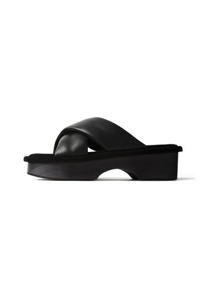 Zwarte slip-on sandaal met gekruiste gewatteerde leren bandjes en een dikke plateauzool met een kleine booguitsnede.