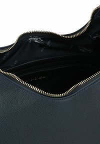 Borsa in pelle testurizzata blu navy con cerniera dorata. Interno con rivestimento in tessuto scuro con motivo a logo ripetuto e più scomparti.